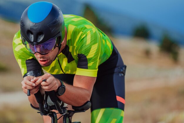 Foto de cerca de un triatleta activo en ropa deportiva y con un casco protector andando en bicicleta. Enfoque selectivo.