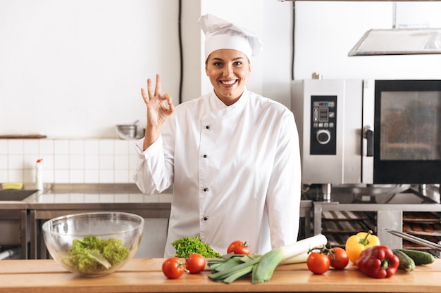 Foto de chef mujer profesional vistiendo uniforme blanco cocinar comida con verduras frescas, en la cocina del restaurante