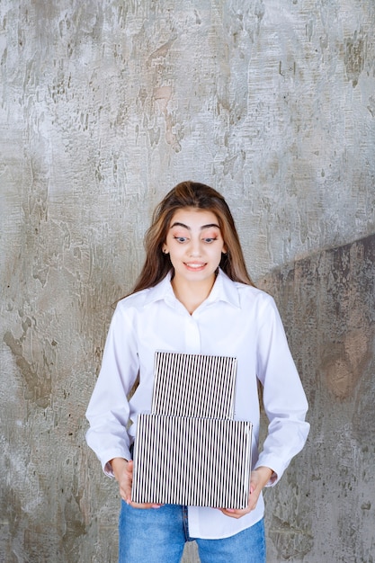 Foto de una chica guapa modelo con cabello largo sosteniendo cajas presentes