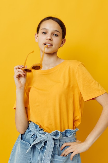 Foto chica guapa en un sombrero amarillo estilo juvenil ropa casual en gafas de sol fondo amarillo