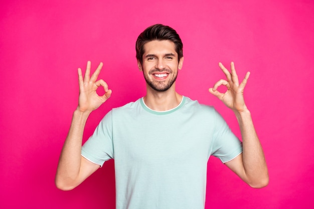 Foto de chico macho divertido que muestra el símbolo okey expresando su acuerdo y actitud positiva, use una camiseta casual aislado de fondo de color rosa vibrante