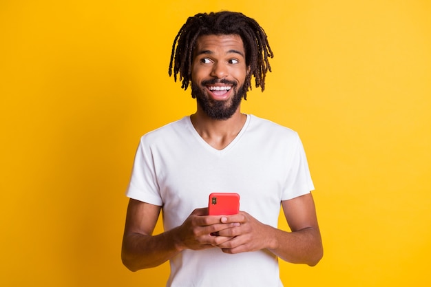 Foto de chico negro mantenga teléfono mirar espacio vacío boca abierta use camiseta blanca fondo de color amarillo aislado