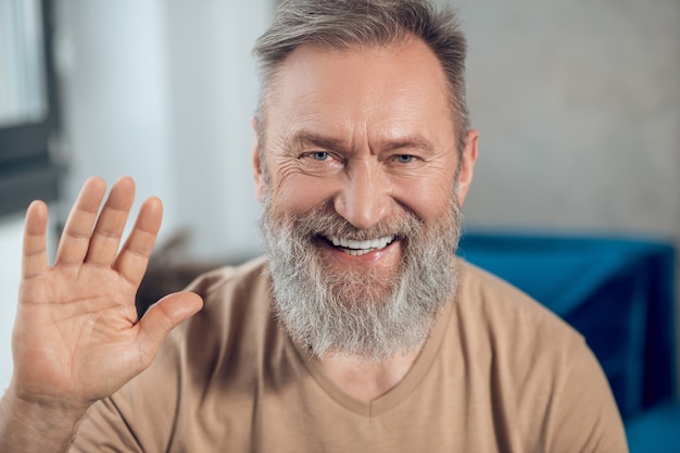 Una foto de cintura para arriba de un hombre barbudo sonriente