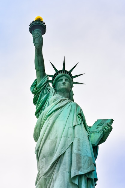 Foto foto close-up da estátua da liberdade em um dia ensolarado e céu azul com nuvens. ilha da liberdade. nyc, eua.