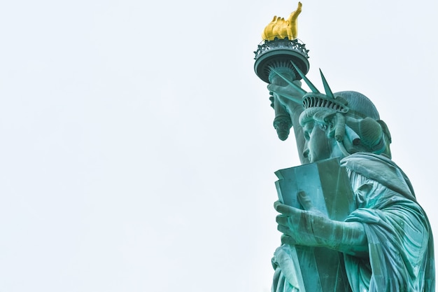 Foto close-up da estátua da liberdade em um dia ensolarado e céu azul com nuvens. ilha da liberdade. nyc, eua.