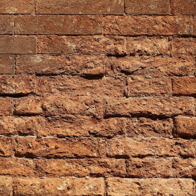 Foto closeup ao ar livre envelhecido terracota áspero texturizado argila tijolo fachada de pedra parede edifício exterior ...