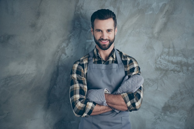 Foto de cocinero positivo alegre divirtiéndose descansar después de un duro día de trabajo con guantes camisa a cuadros con una gran sonrisa pared gris aislada pared de color concreto