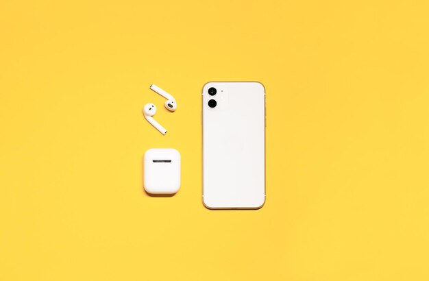 foto com fones de ouvido sem fio de smartphone branco e estojo de carregamento em um fundo amarelo isolado