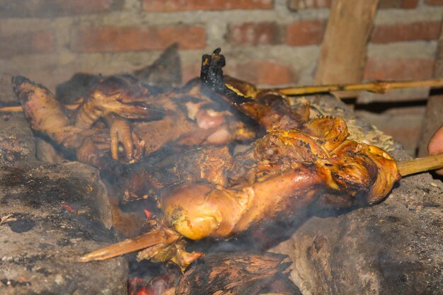 Foto de comida tradicional indonesia un gallo siendo asado con humo ondulante