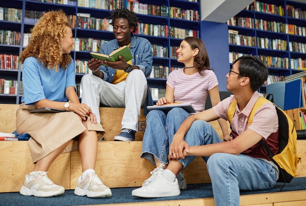 Foto completa de estudantes multiétnicos estudando juntos na biblioteca com cores azuis vibrantes