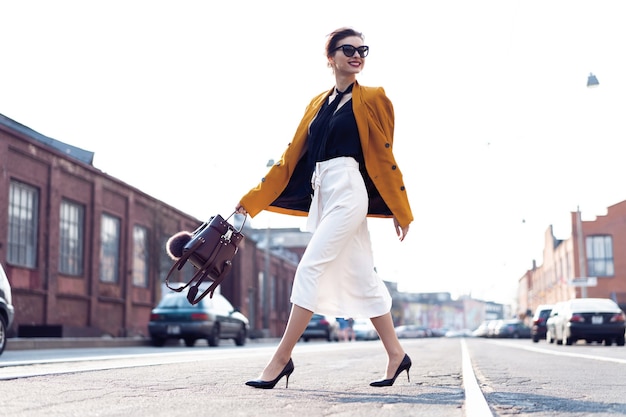 Foto completa de uma elegante jovem mulher de negócios feliz andando na rua