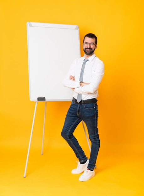 Foto completa do empresário dando uma apresentação no quadro branco sobre amarelo isolado com óculos e sorrindo