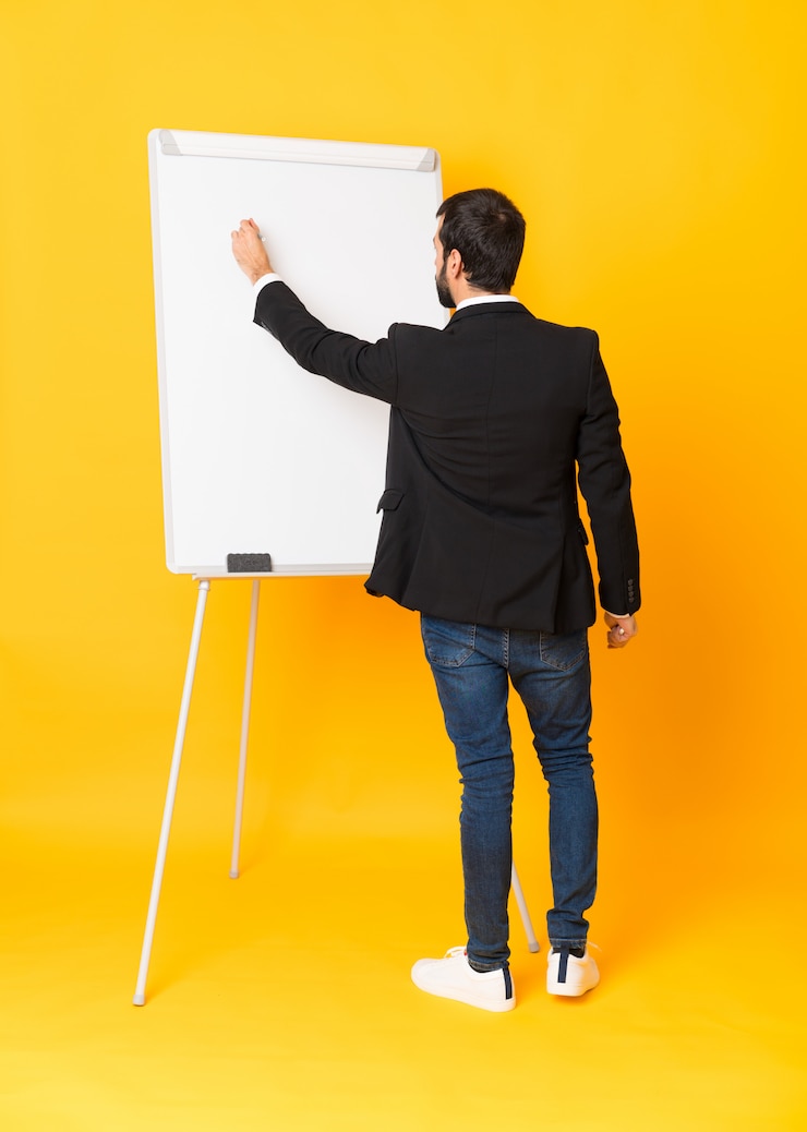 Foto foto completa do empresário dando uma apresentação no quadro branco sobre amarelo isolado