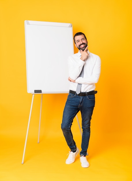 Foto completa do empresário dando uma apresentação no quadro branco sobre amarelo sorrindo