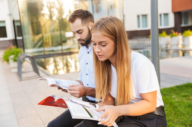 Foto de un concentrado jóvenes estudiantes colegas en la calle estudiando sosteniendo cuadernos.