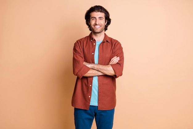 Foto de confianza joven de brazos cruzados radiante sonrisa desgaste camiseta marrón pantalones azules aislados de fondo de color beige