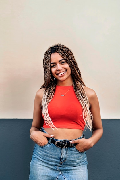 Foto conservada em estoque da jovem mulher afro-americana, sorrindo e olhando para a câmera. Ela tem tranças legais.