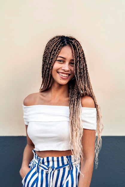 Foto conservada em estoque da jovem mulher afro-americana, sorrindo e olhando para a câmera. Ela tem tranças legais.