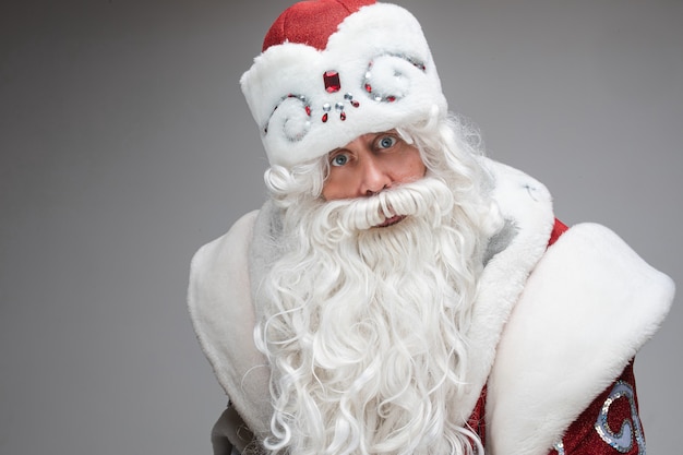 Foto conservada em estoque de Father Frost, infeliz ou descontente, em traje tradicional chique, olhando para a câmera com os olhos arregalados e os braços cruzados. Conceito de greve.