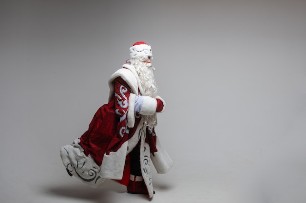 Foto conservada em estoque de sorrindo feliz Papai Noel com chapéu tradicional com strass e longa barba branca, olhando para a câmera. Recorte em fundo vermelho. Conceito de felicidade.