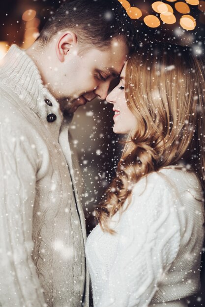 Foto foto conservada em estoque de um casal encantador, cara a cara e sorrindo sob a neve.