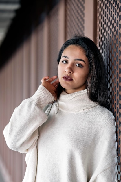 Foto conservada em estoque de uma jovem mulher de negócios, olhando para a câmera a sério. Ela está parada na rua.