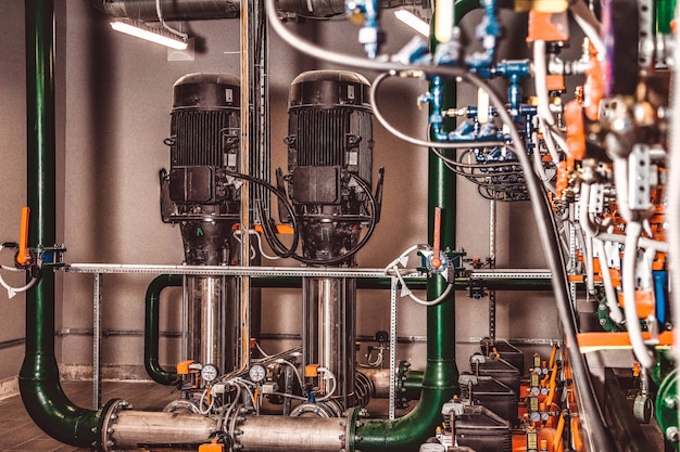 La foto contiene grano de película. Estación de bombeo de agua y tubería con tanques en una sala industrial para suministrar agua a alta presión para tareas de extinción de incendios. Tuberías de rociadores y sistema de control para proporcionar agua potable