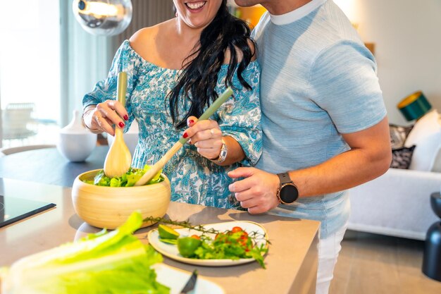 Foto cortada de cerca de una pareja preparando ensalada en un nuevo hogar juntos