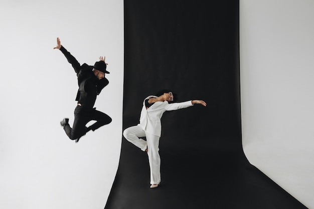 Foto creativa de un hombre europeo con traje negro y una joven afroamericana con el pelo rizado