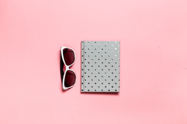 Foto creativa plana del escritorio del espacio de trabajo con anteojos de cuaderno color aguamarina cactus con espacio de copia fondo rosa estilo minimalista
