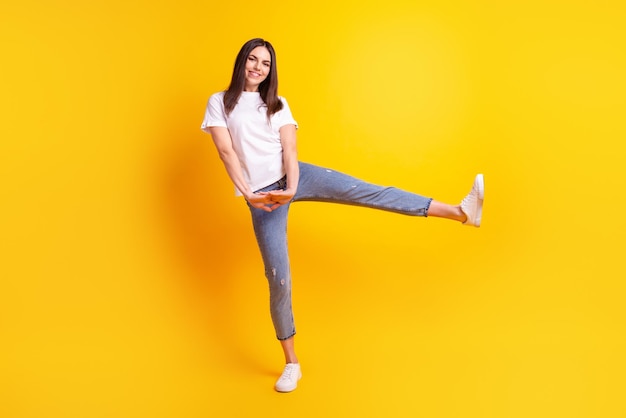 Foto de cuerpo completo de una mujer joven y bonita que se divierte bailando con ropa informal aislada sobre un fondo de color amarillo