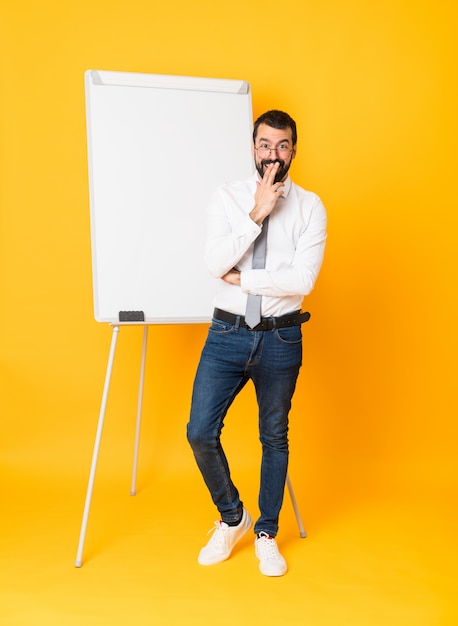 Foto de cuerpo entero del empresario dando una presentación en pizarra sobre amarillo con gafas y sorprendido