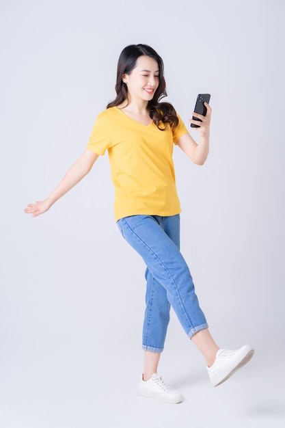 Foto de cuerpo entero de la joven mujer asiática de pie sobre fondo blanco.