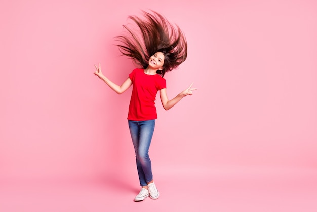 Foto de cuerpo entero de una niña latina con cabello al viento hace que el signo v use un atuendo de estilo casual aislado sobre fondo de color pastel