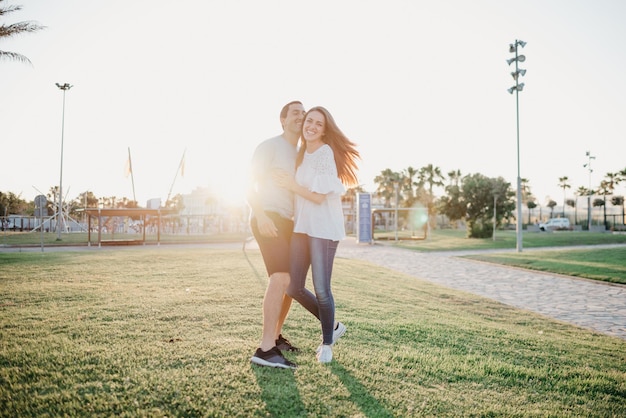 Una foto de cuerpo entero de una niña sonriente que baila con su novio hispano entre palmeras