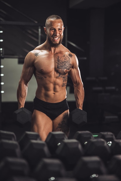 Una foto de un culturista musculoso entrenando duro con pesas en el gimnasio.