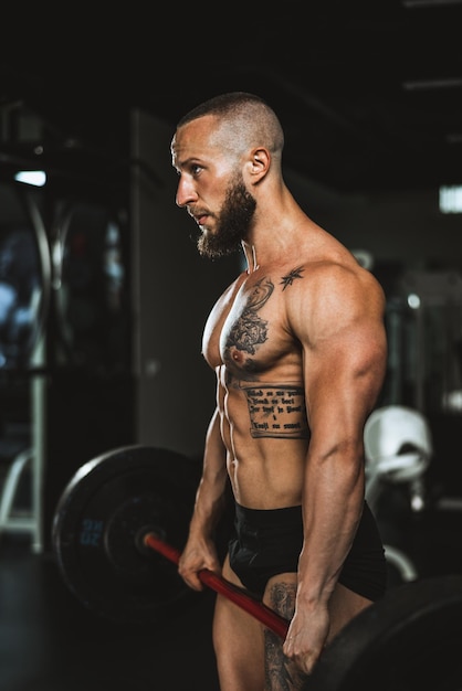 Una foto de un culturista musculoso entrenando duro con pesas en el gimnasio.