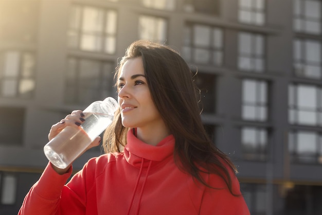 Foto da bela corredora em pé ao ar livre segurando uma garrafa de água