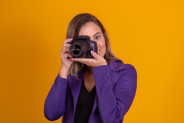 Foto da câmera do fotógrafo fotografando a alegria da menina faz a fotografia tomando o conceito garota com uma câmera mulher segurando a câmera sobre fundo amarelo garota usando uma foto da câmera