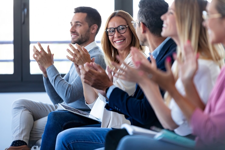 Foto foto da equipe de negócios feliz batendo palmas depois de ouvir a conferência enquanto está sentado no espaço de coworking.