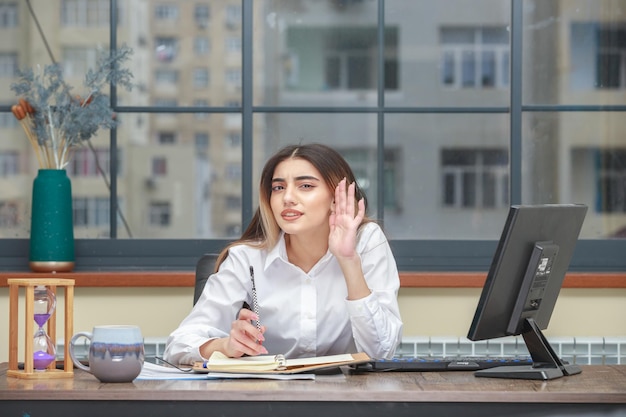 Foto da garota oyun sentada na mesa e tentando ouvir