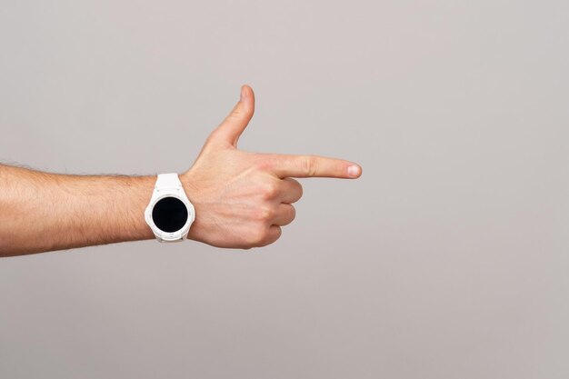 Foto da mão masculina com smartwatch apontando para copyspace sobre fundo cinza