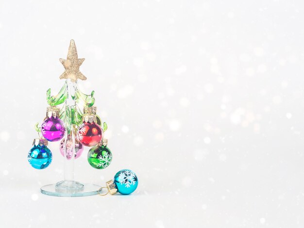 Foto da véspera de Ano Novo com uma árvore de Natal de vidro decorada com brinquedos em pé sobre um fundo branco com bokeh Há espaço para texto