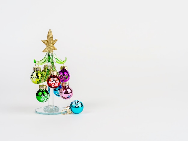 Foto da véspera de Ano Novo com uma árvore de Natal de vidro decorada com brinquedos em pé sobre um fundo branco Há espaço para texto