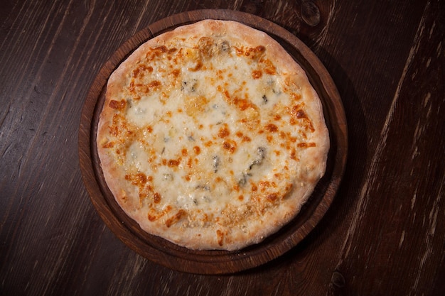 Foto da vista de cima da deliciosa pizza quattro formaggi em uma mesa de madeira