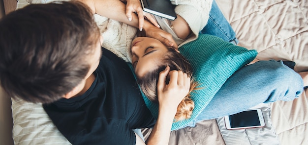 Foto da vista superior de uma jovem deitada sobre os pés do amante enquanto passa um tempo na cama