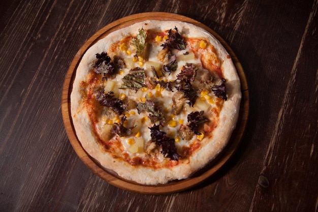 Foto da vista superior de uma saborosa pizza vegana em uma mesa de madeira recém saída do forno