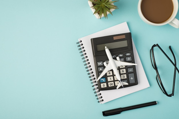 Foto da vista superior do modelo de aeronave em óculos de caneta organizador de vaso de flores de xícara calculadora em fundo azul pastel isolado com copyspace