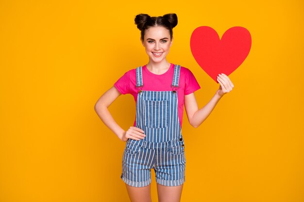 Foto de una dama adolescente mantenga una gran invitación de fecha creativa de corazón de papel aislado sobre fondo amarillo