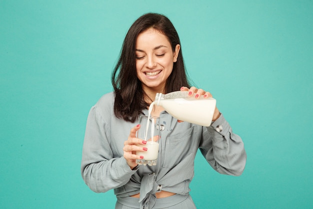 Foto de dama atractiva vierte leche en vidrio, productos lácteos